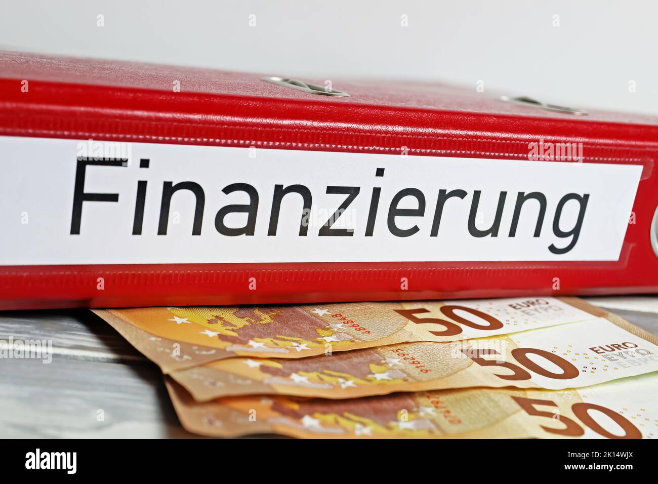 Nahaufnahme eines isolierten roten Dateiordners mit dem deutschen Wort Finanzierung Übersetzung: Finanzierung), Euro-Geldscheine Stockfoto