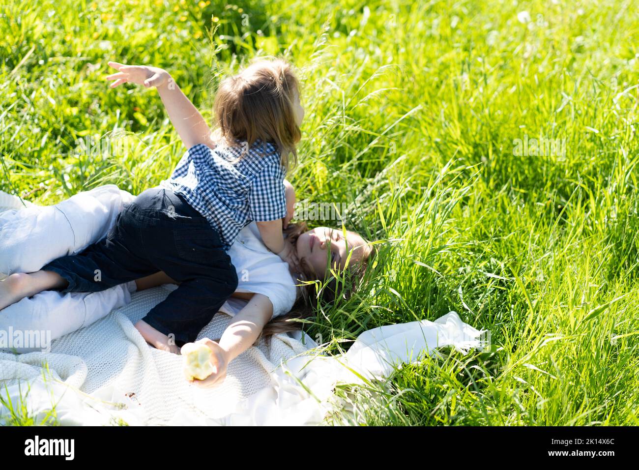 Bruder und Schwester umarmen und lachen fröhlich, liegen auf dem grünen Gras. Die Sonne scheint, die Kinder sind unbeschwert glücklich. Das Konzept eines glücklichen Familienlebens und der Bindung. Speicherplatz kopieren. Stockfoto