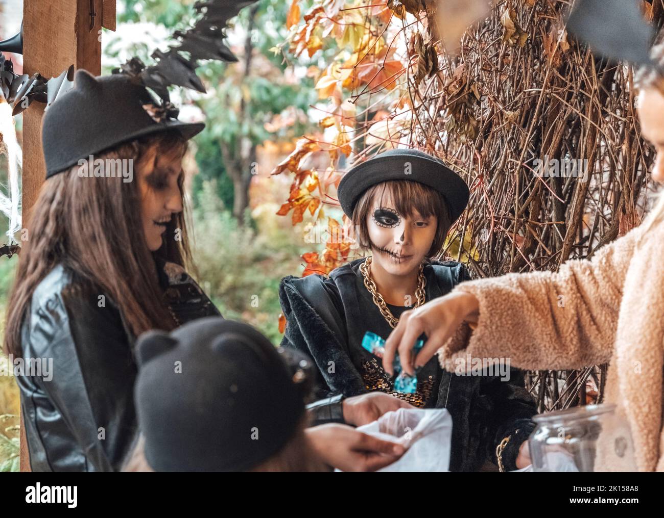 Unheimlich Mädchen, Schwestern, Freunde feiern halloween. Spielen Treak oder Treat Spiel auf der Veranda mit Girlande. Taschen mit Süßigkeiten in den Händen.erschreckend Gesicht skul Stockfoto