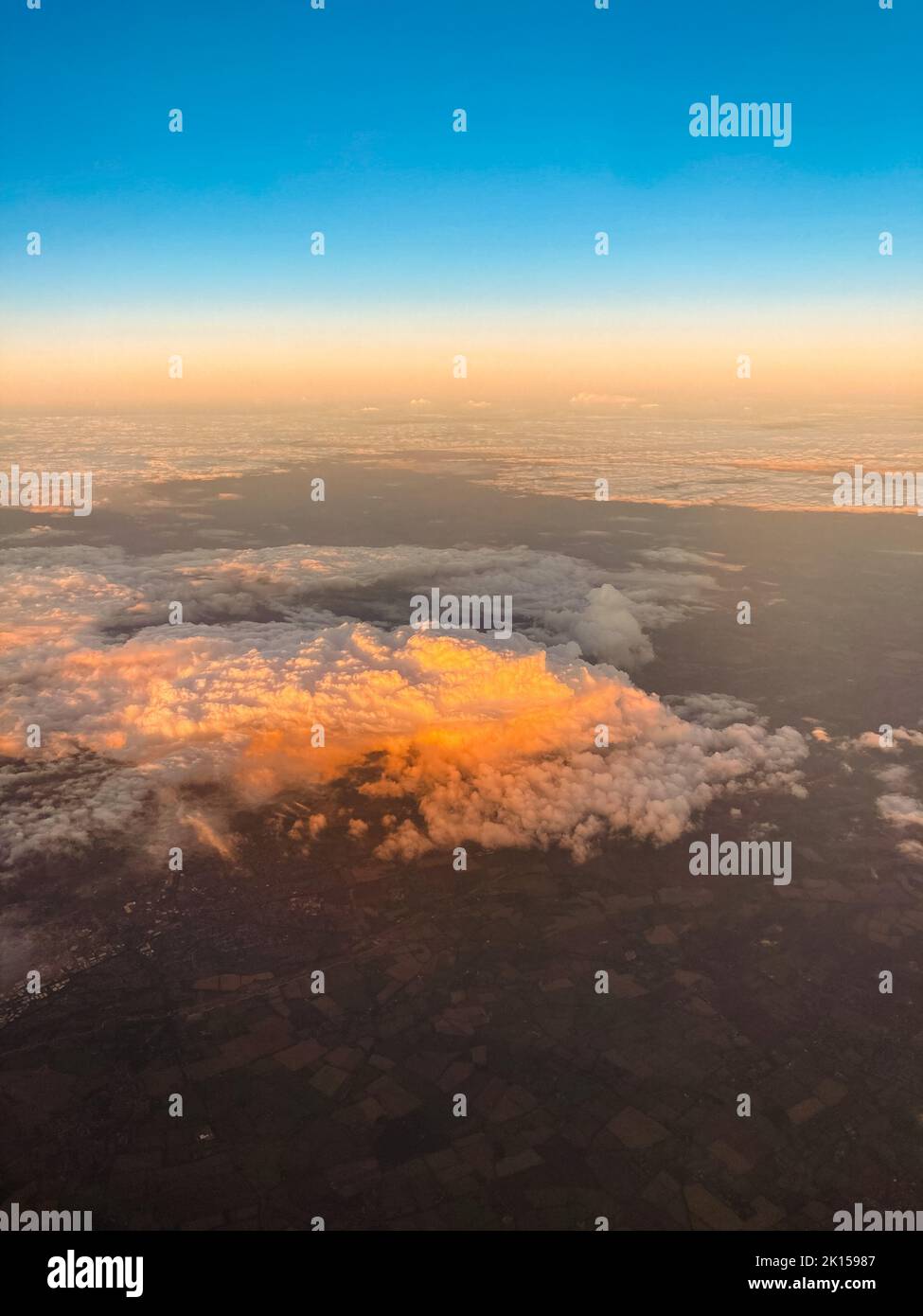 Atemberaubende Aussicht auf weiße, flauschige Wolken am Himmel von einem Flugzeug aus bei Sonnenuntergang Stockfoto