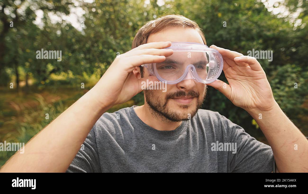 Lächelnder Profi-Mäher mit transparentem Brillenschutz und isolierenden Kopfhörern. Stockfoto