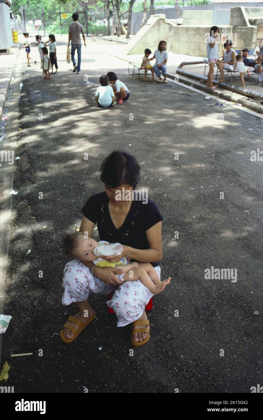 Eine vietnamesische Frau füttert ihr Kind in einem Flüchtlingslager in Kai Tak, Hongkong, mit einer Flasche. Stockfoto