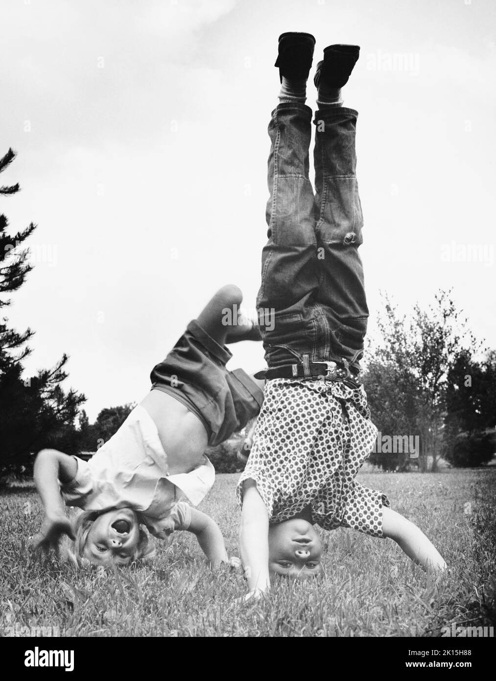 Ein Mädchen versucht erfolglos, wie ihr Freund einen Kopfstand zu machen. Ca. 1950, 1960. Stockfoto