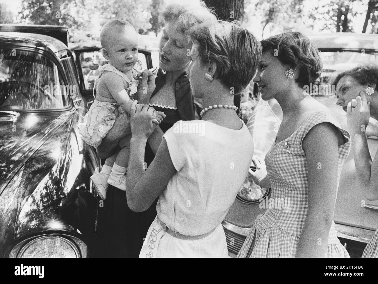 Junge texanische Frauen bewundern das Baby eines Freundes auf ihrer Schulhomecoming, 1950s. Lovelady, Texas. Stockfoto