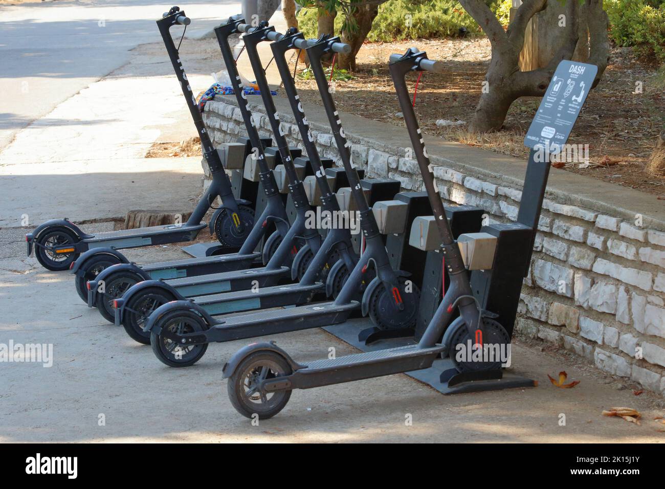 Eine Reihe von Dash E-Scootern, die über ein automatisiertes Sharing-System aufgeladen werden Stockfoto