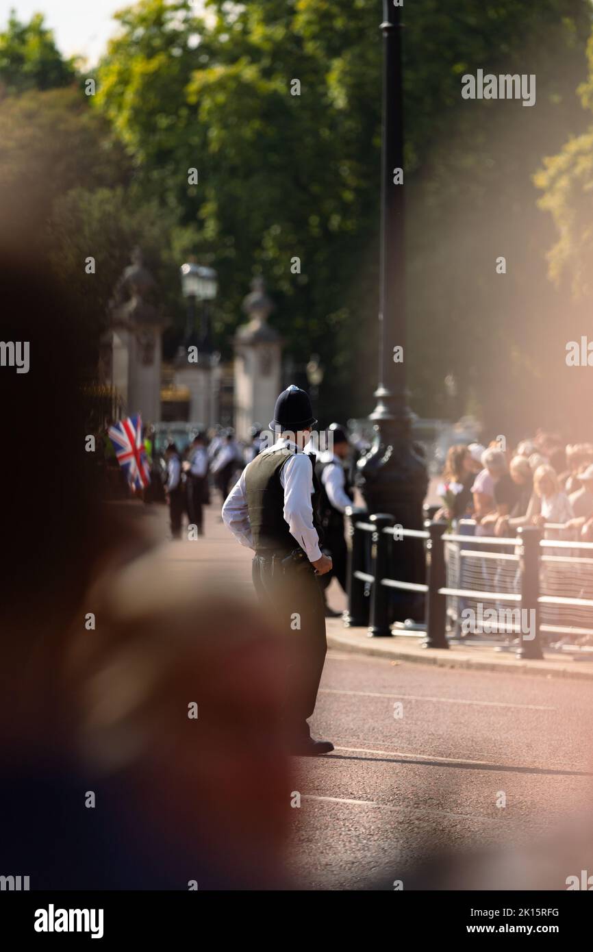 Polizeibeamter, der vor dem Buckingham Palace steht und die Öffentlichkeit und den Palast wenige Tage nach dem Tod von Königin Elizabeth II. Schützt Stockfoto