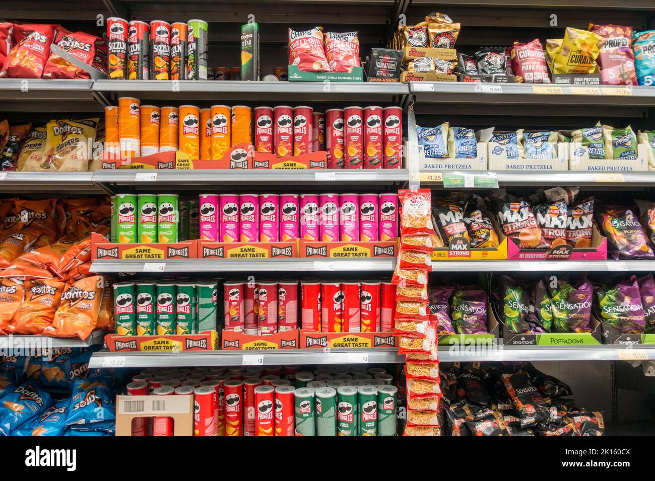 Supermarktregal gefüllt mit ungesunden Chips und herzhaften Snacks Stockfoto