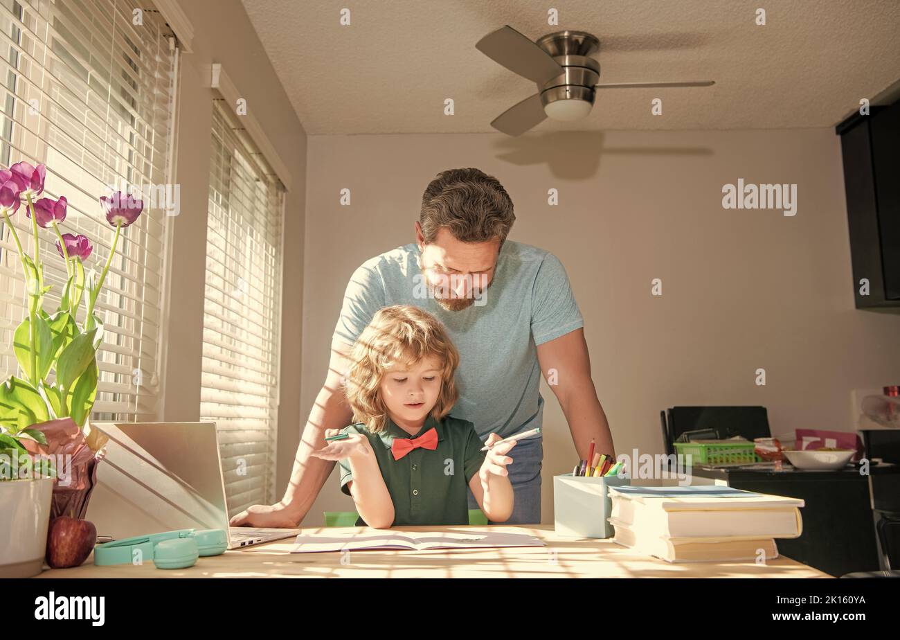 Bärtiger Vater schreibt Schulaufgaben mit seinem Jungen Sohn im Klassenzimmer, Schulunterricht Stockfoto