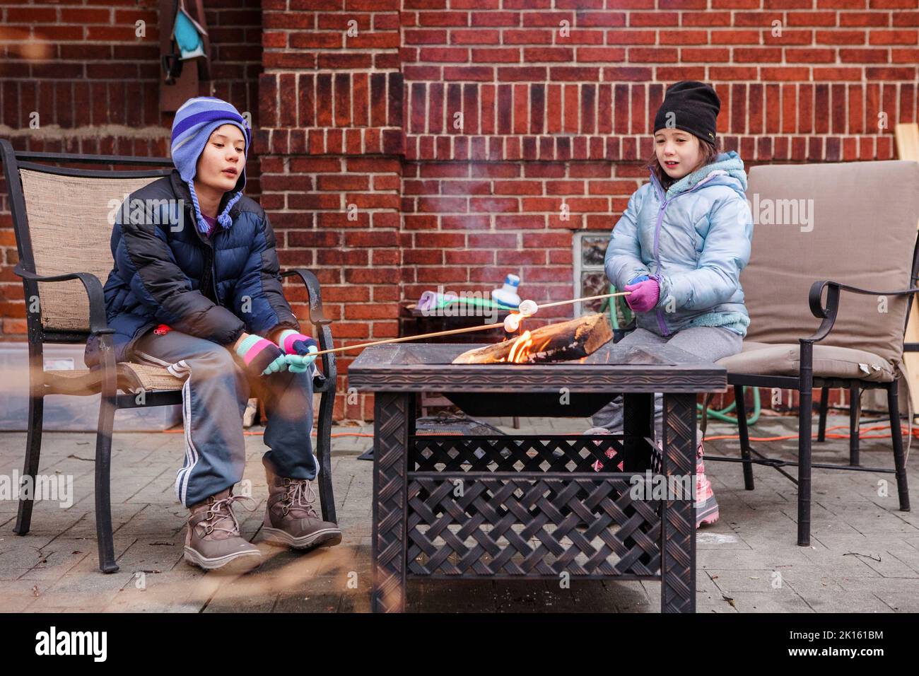 Zwei Kinder rösten im Winter über der Feuerstelle im Hinterhof Sumpflandschaften Stockfoto