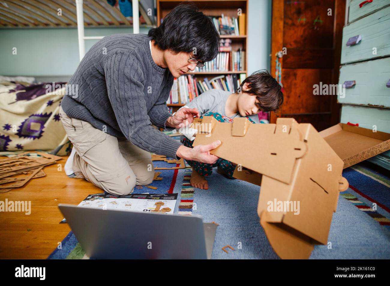 Ein Vater und ein Sohn bauen zusammen mit Pappe eine Struktur Stockfoto