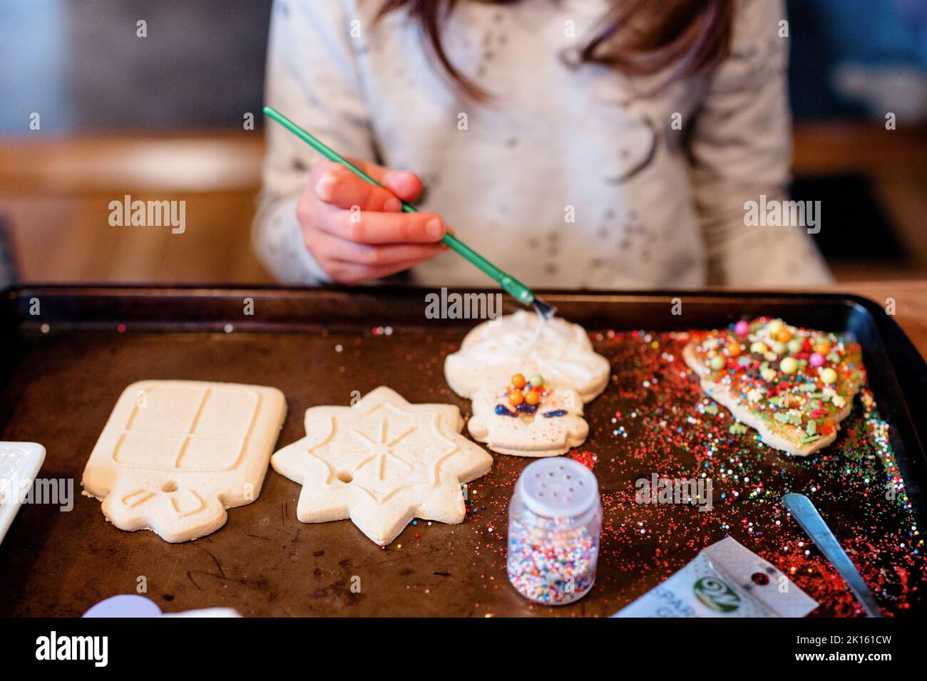 Ein Kind dekoriert ein unordentliches Tablett mit weihnachtskeksen Stockfoto
