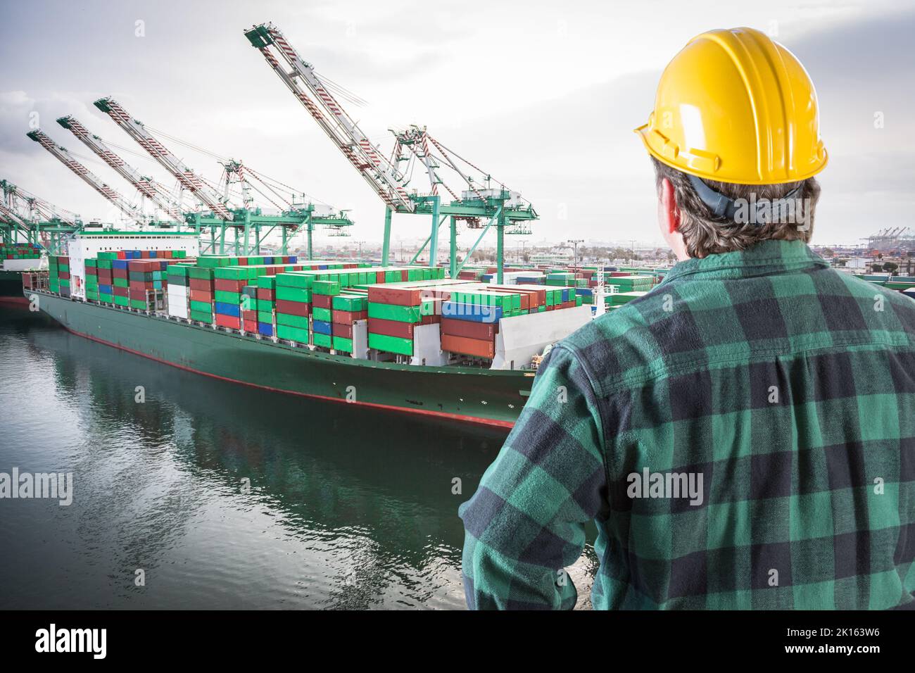 Männlicher Arbeiter mit gelbem Hut und Blick auf den San Pedro-Schiffshof. Stockfoto