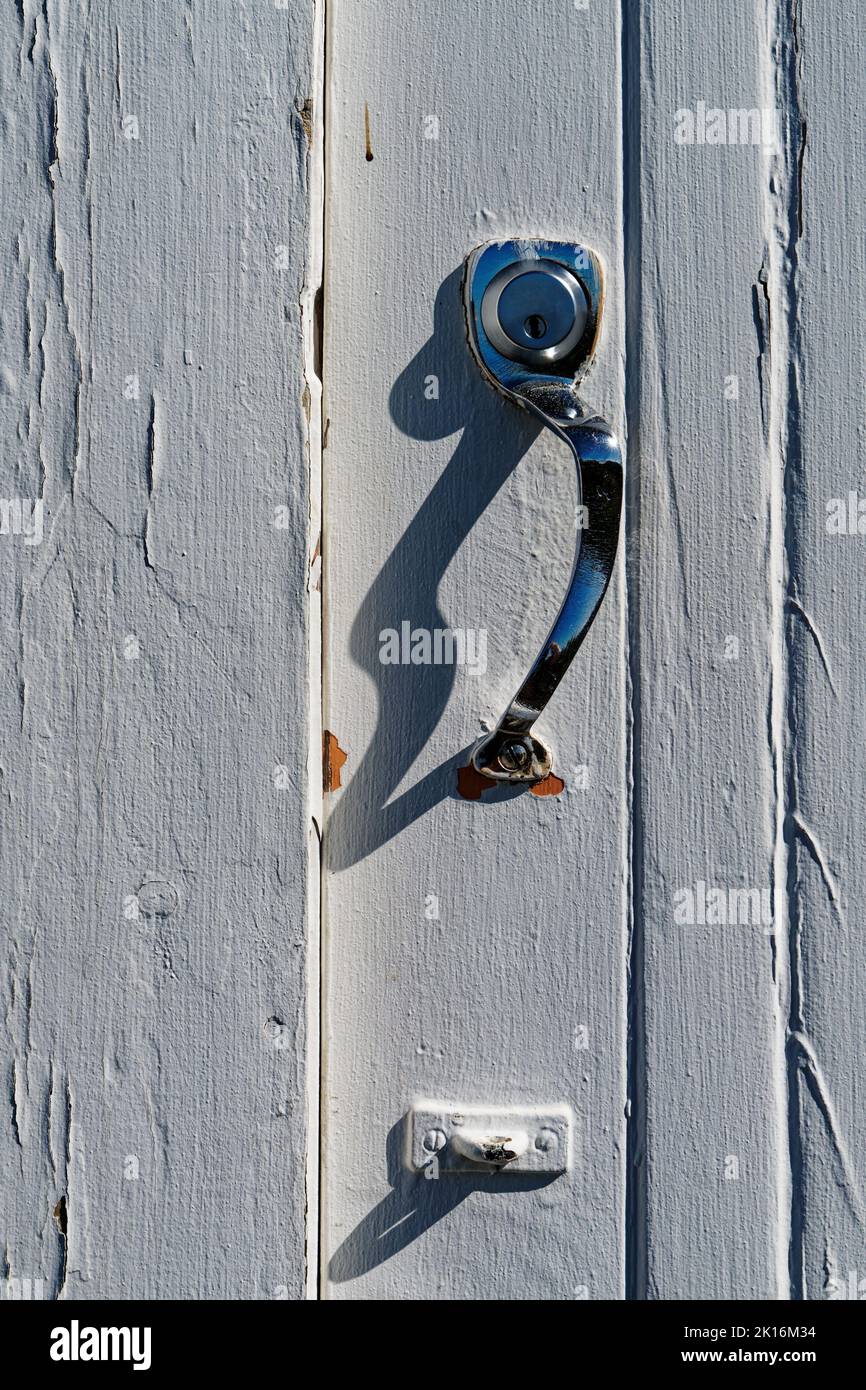 Türschloss an einem Industriegebäude mit Chromgriff. Ein Auge unten für einen Türhaken. Stockfoto