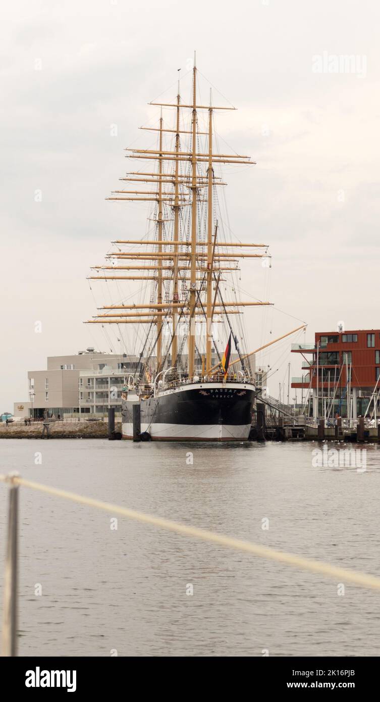 Pamir - P Liner Class - Ein majestätisches Großschiff mit hoch aufragenden Masten liegt am Hafen, umgeben von modernen Gebäuden und ruhigem Wasser. Stockfoto