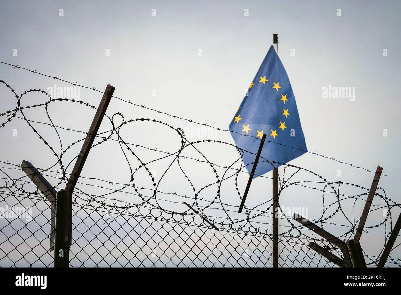 Blick auf die Flagge der Europäischen Union hinter Stacheldraht gegen bewölkten Himmel. Konzept anti-russische Sanktionen. Grenzposten an der Grenze zu Russland. cancel Kultur Rus Stockfoto