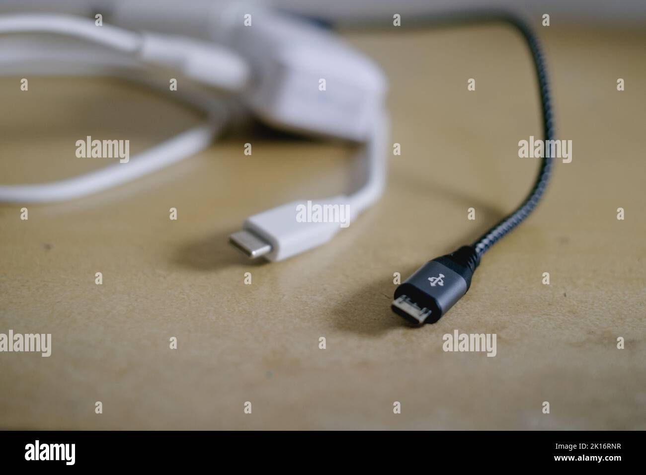 Schwarz-Weiß-Schnellladegeräte für Mobiltelefone für Android-Telefone mit abnehmbaren USB-auf-Micro-USB-Datenkabeln auf dem Tisch. Selektiver Fokus. Stockfoto