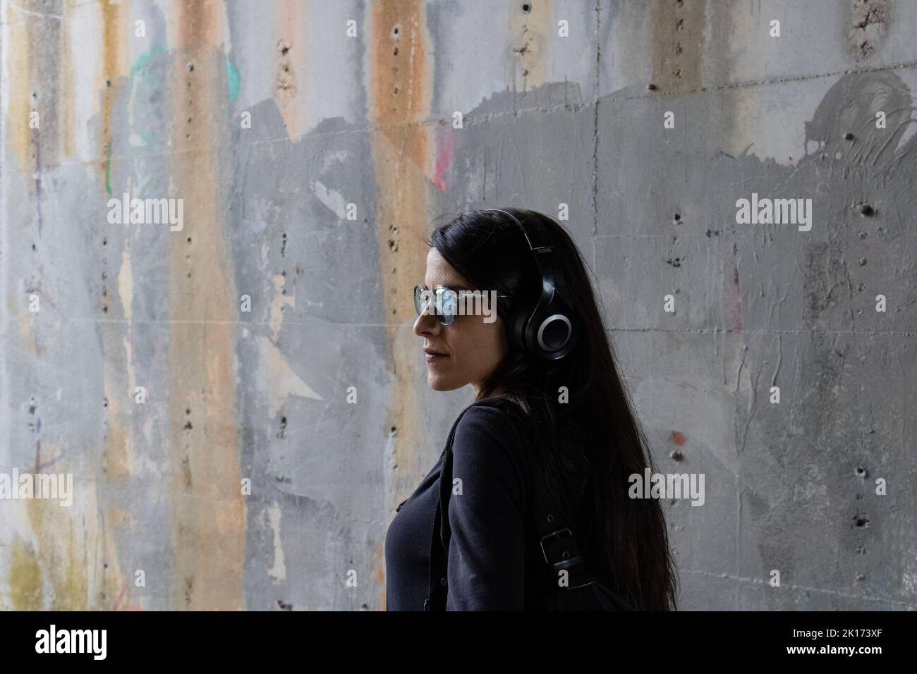 Frauen vor einer Betonwand mit Sonnenbrille und Kopfhörern Stockfoto