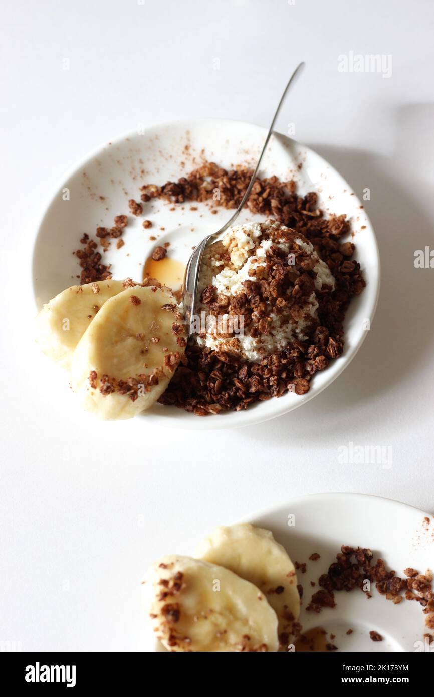 Frühstücksteller mit Hüttenkäse mit Müsli, Honig und Banane. Gesundes Dessert-Food-Konzept. Stockfoto