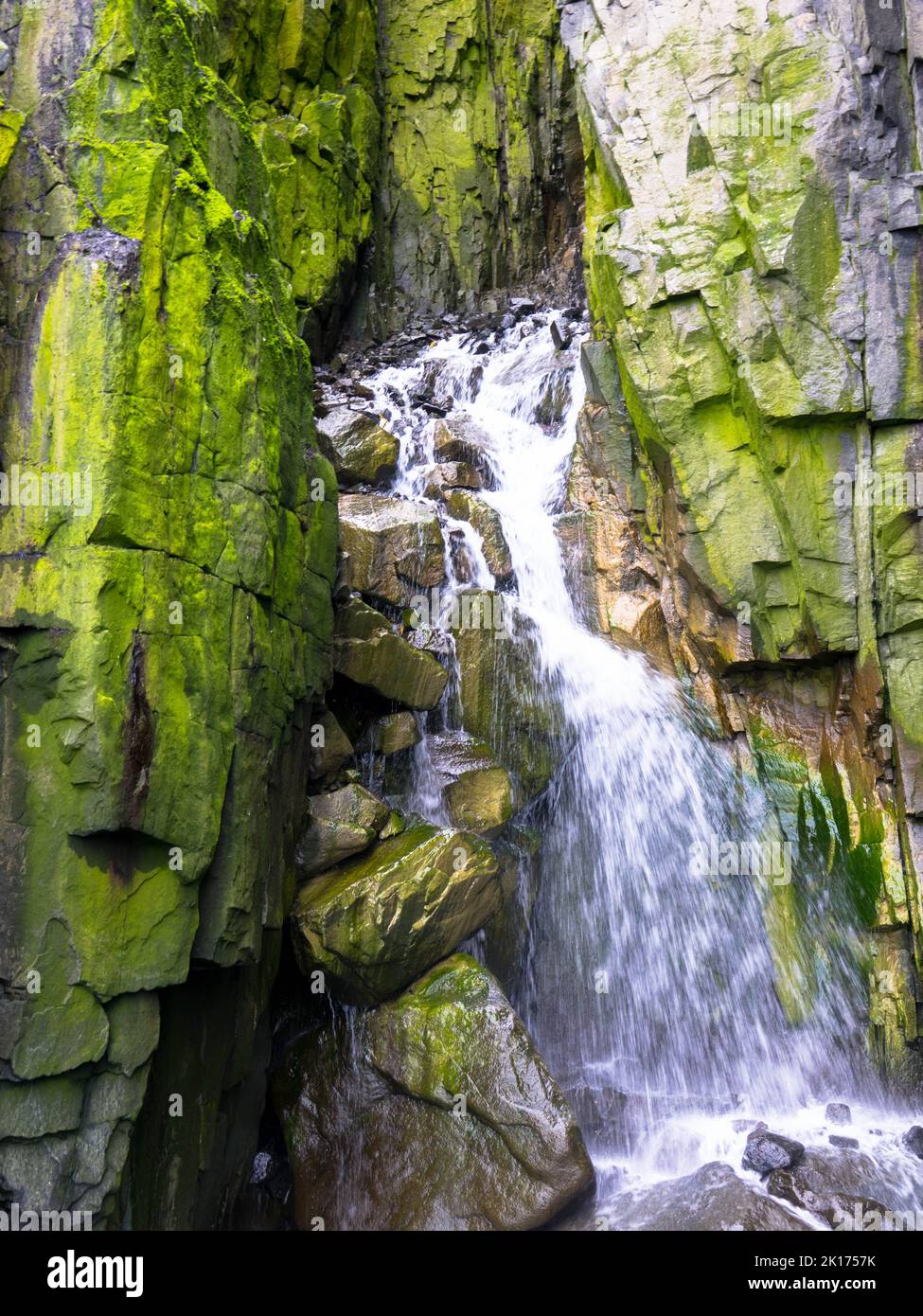 Spektakuläre Aussicht auf einen Wasserfall auf einem Gletscher. Die Vogelklippe Alkefjellet ist die berühmteste Klippe des Spitzbergen-Archipels. Hinloopen Fjord, Spitzbergen. Stockfoto