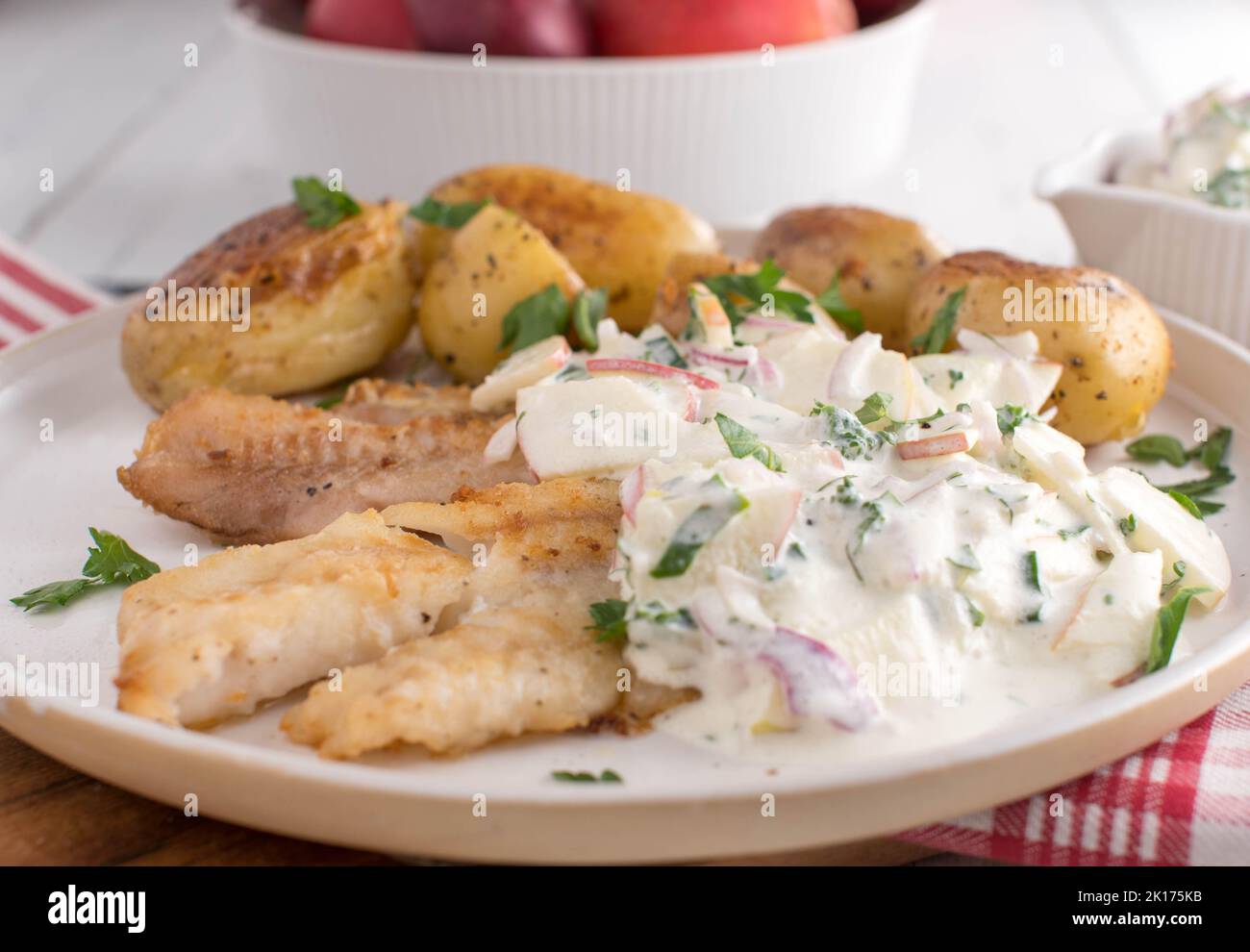 Leichtes Fischgericht mit gebratenem Rotbarsch-Filet. Serviert mit gerösteten Mantelkartoffeln und einer köstlichen sauren Rahmsoße mit Kräutern und Äpfeln auf einem Teller Stockfoto