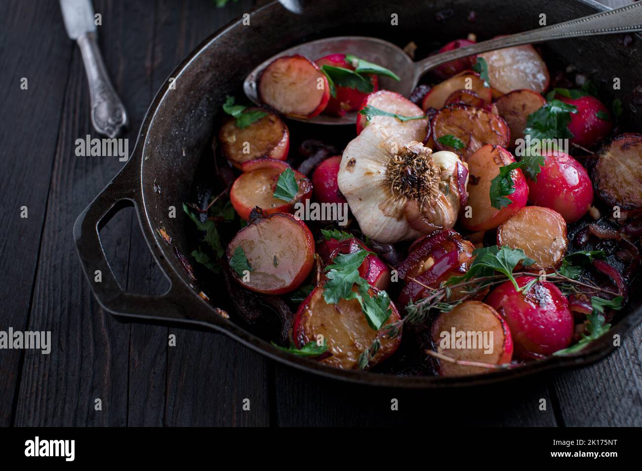 In der Pfanne geröstete Gemüsegeräte mit karamellisiertem rotem Rettich, roten Zwiebeln, Knoblauch, Olivenöl und Parley. Serviert und gekocht in einer gusseisernen Pfanne Stockfoto