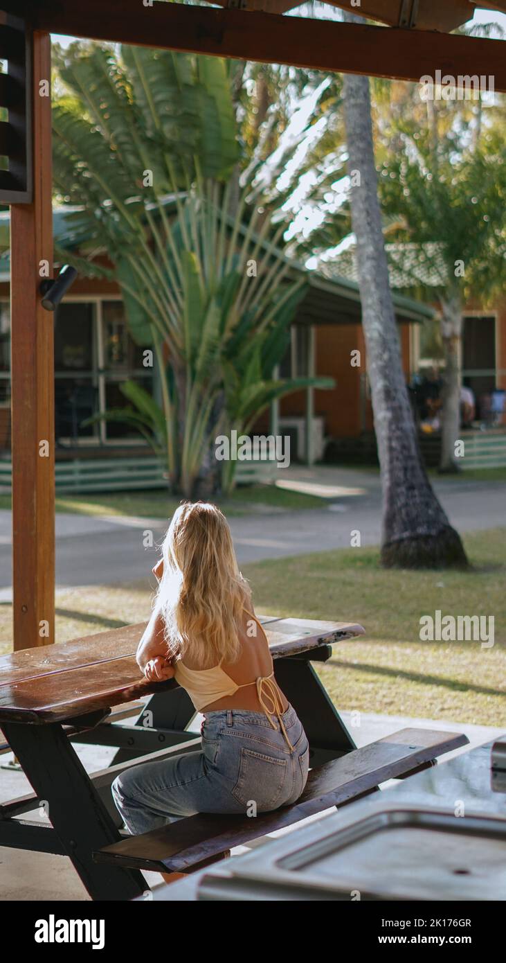 Portraitfotografie eines blonden Mädchens in blauer Jeans und gelbem Oberteil in einem Ferienpark in Queensland, Australien. Sie erkundet den Park. Stockfoto