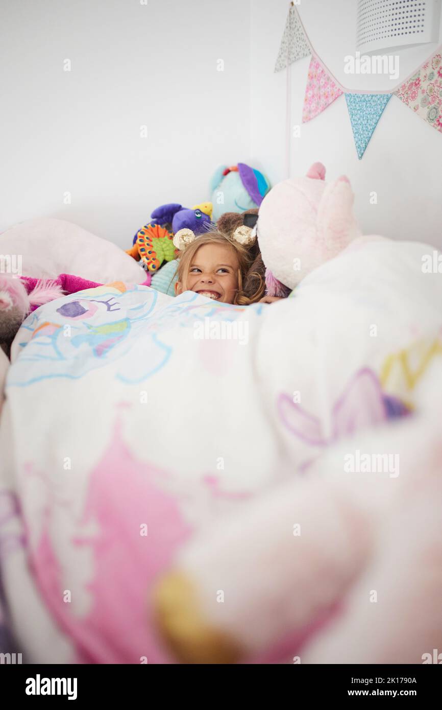 Lächelndes Mädchen im Bett liegend Stockfoto