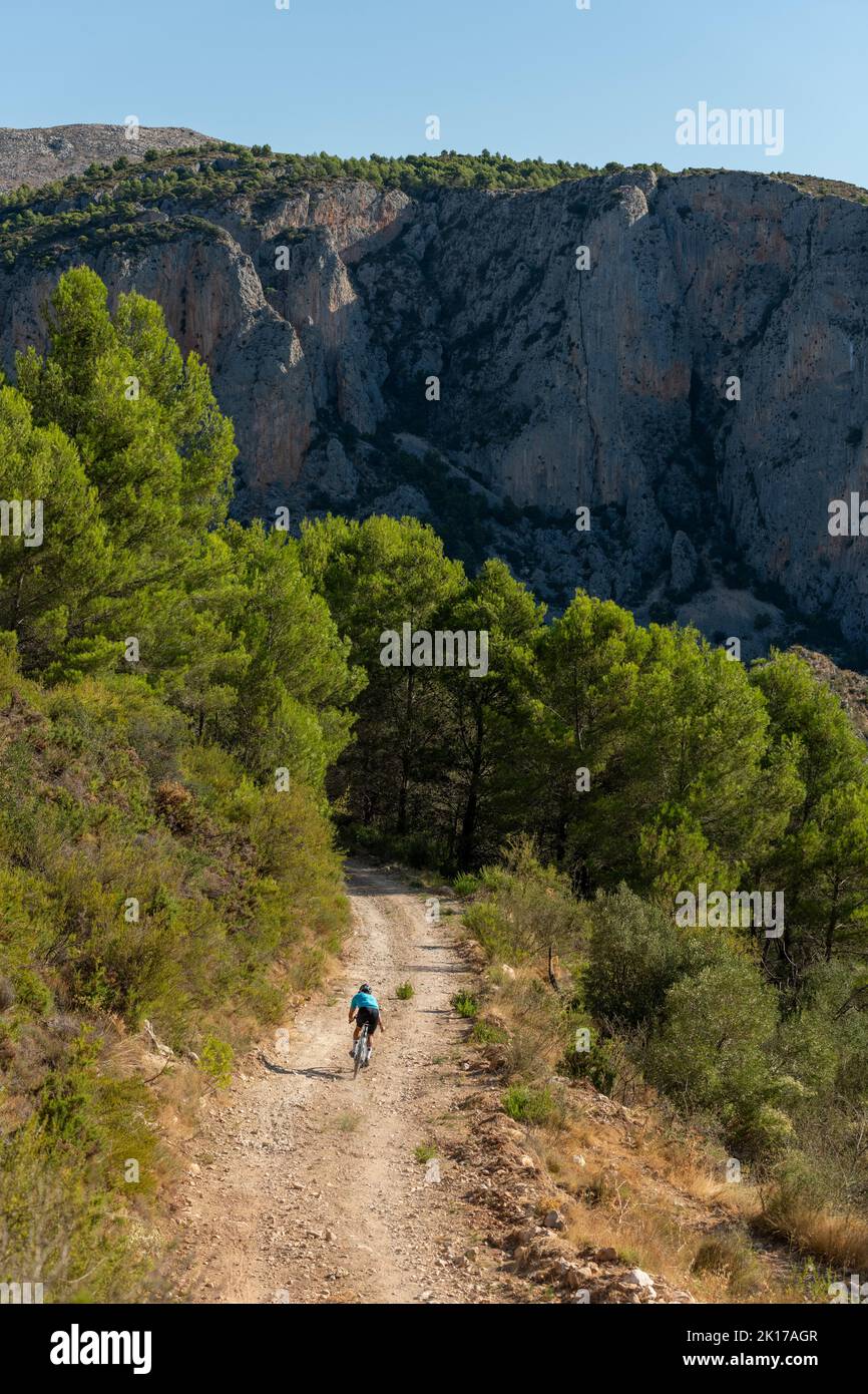 Ein Radler auf einer Schotterstraße mit dem Fahrrad in den Bergen der Costa Blanca, Alicante, Spanien Stockfoto