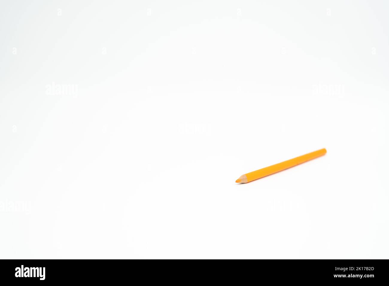 Orangefarbener Bleistift aus Holz auf weißem Hintergrund mit einem Punkt (Blei) im Fokus Stockfoto