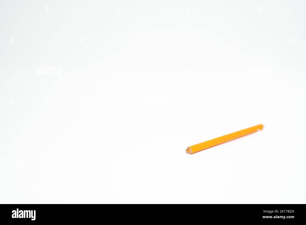 Orangefarbener Bleistift aus Holz auf weißem Hintergrund mit Schwerpunkt am Ende Stockfoto