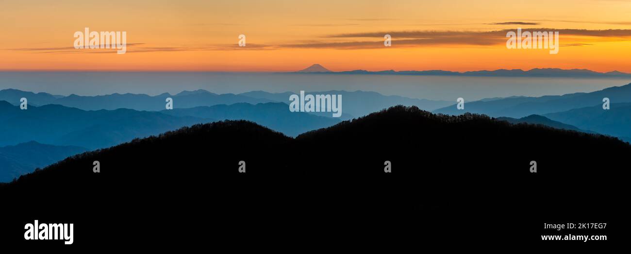 Eine Panoramaaufnahme der Berge unter dem orangefarbenen Sonnenuntergangshimmel Stockfoto