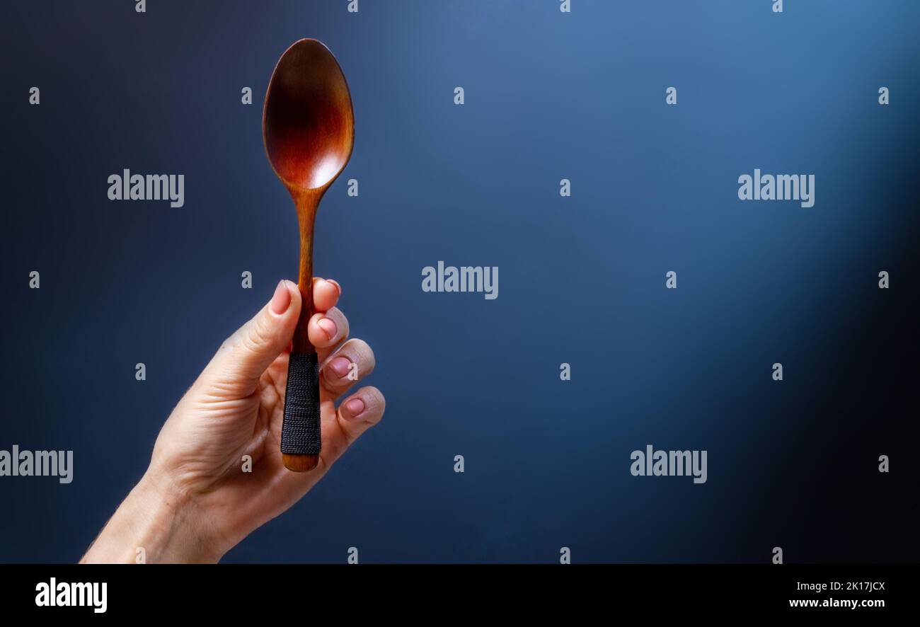 Hand hält Holzlöffel Stockfoto