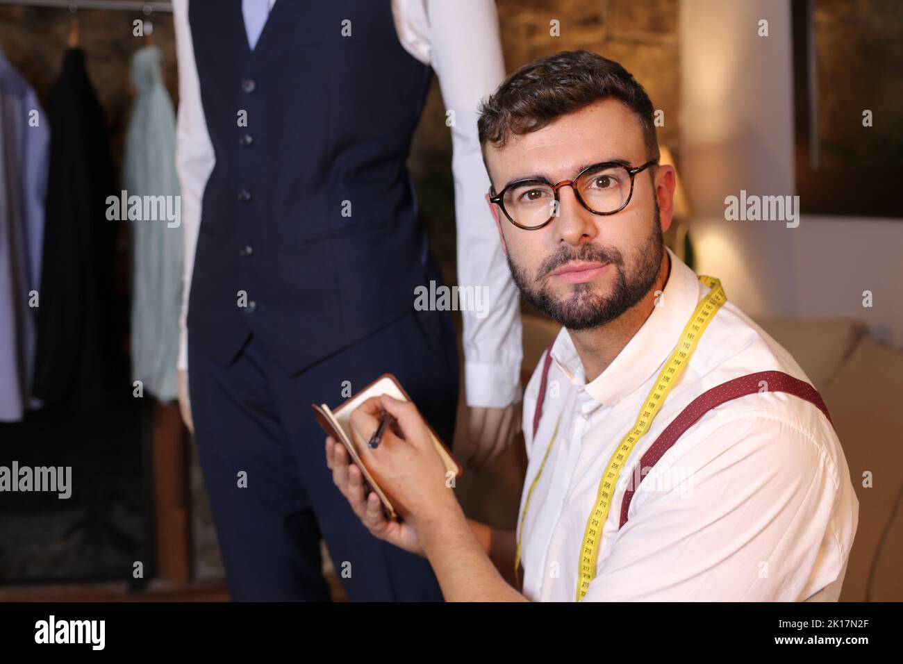 Modedesignerin notiert auf traditionellem Notizblock Stockfoto