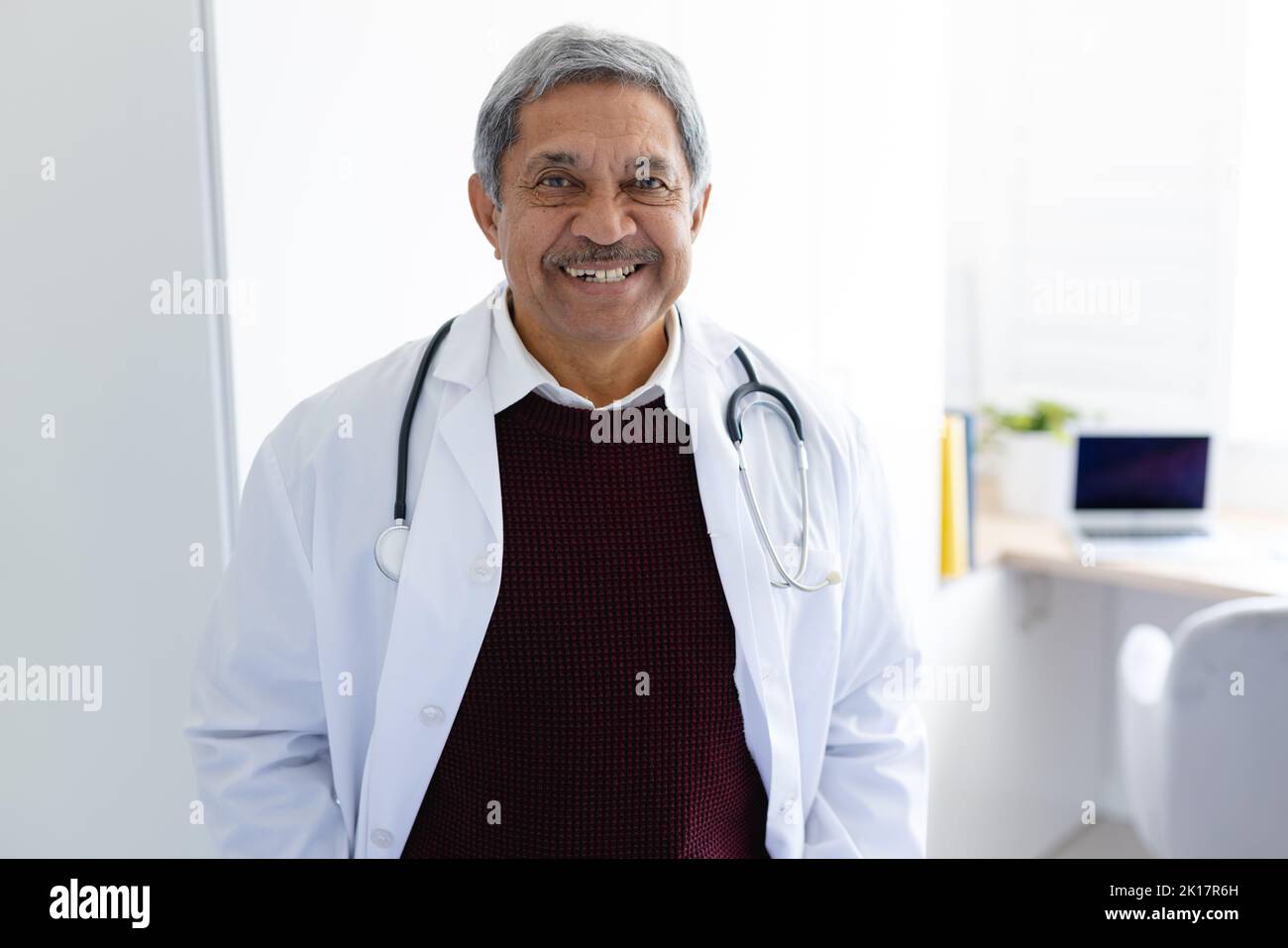 Porträt eines lächelnden, älteren biracial männlichen Arztes mit Stethoskop und weißem Mantel Stockfoto