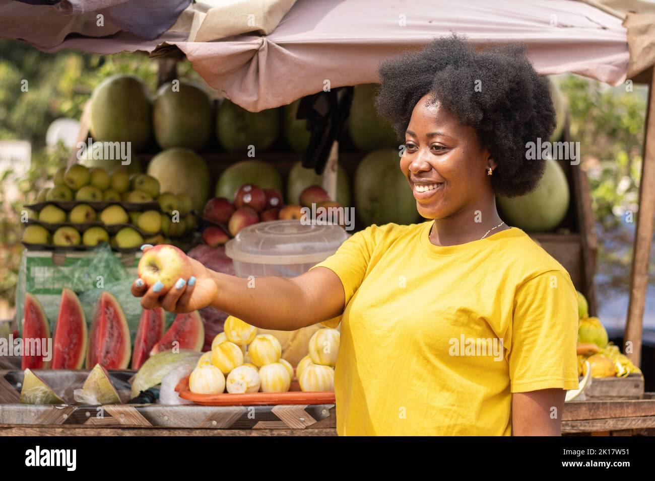 afrikanische Frau auf einem Markt mit einem Apfel Stockfoto