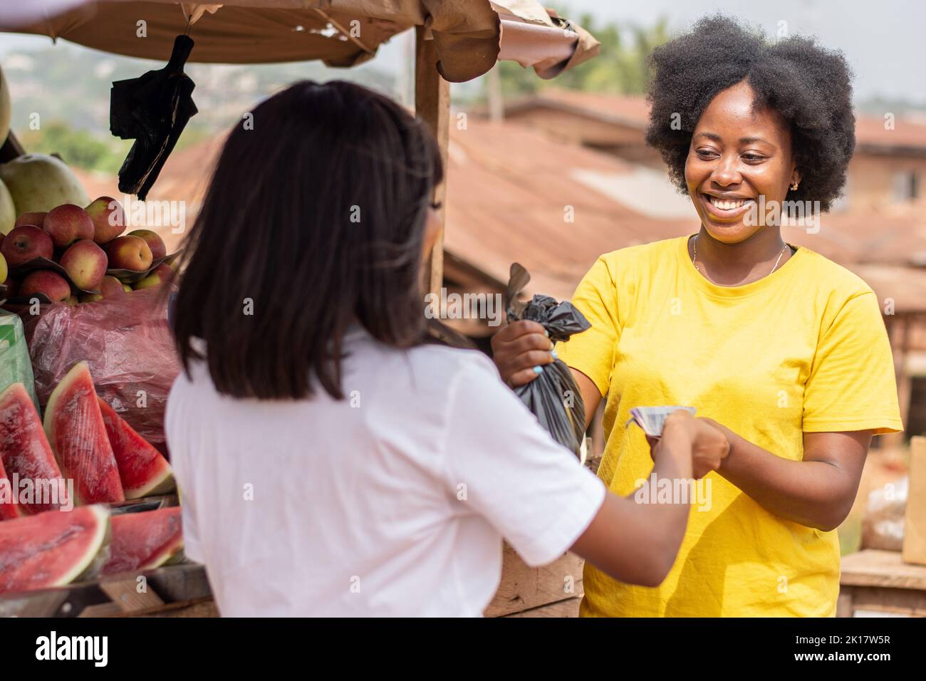 afrikanische Dame, die Früchte von einer Marktfrau kauft Stockfoto