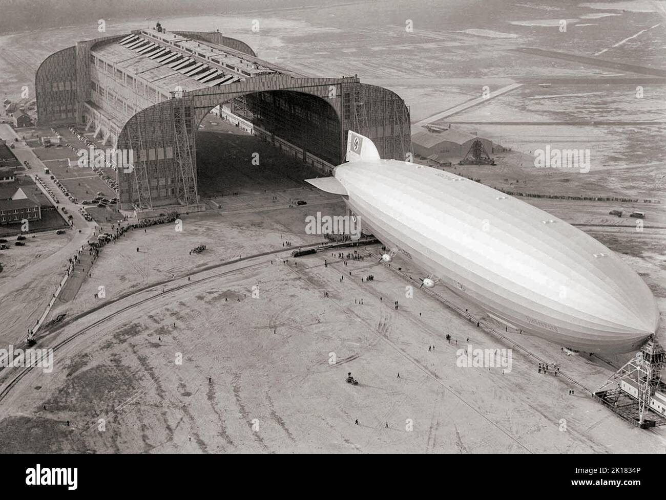 Ein in Deutschland erbauter Zeppelin Hindenburg, der am 9. Mai 1936 in den Hangar der US-Marine eindringt, dessen Nase an den beweglichen Ankerturm in Lakehurst, New Jersey, angespannt ist. Das starre Luftschiff hatte gerade einen Rekord für seine erste Nordatlantiküberquerung aufgestellt, die erste Etappe von zehn geplanten Rundfahrten zwischen Deutschland und Amerika. Stockfoto