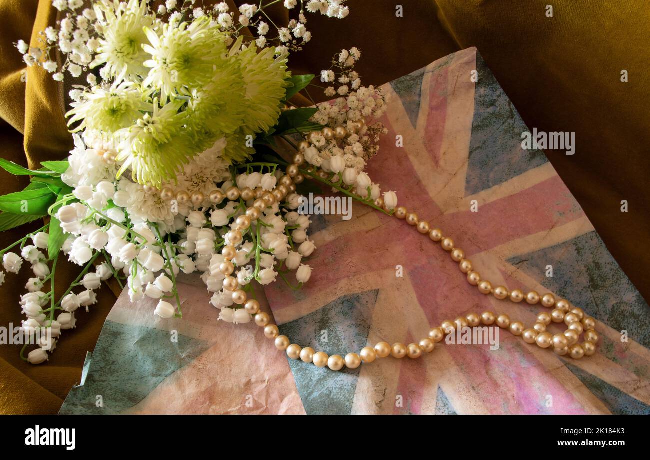 Verblasste Union Jack mit Maiglöckchen und Perlen für den Tod von Königin Elizabeth II Stockfoto