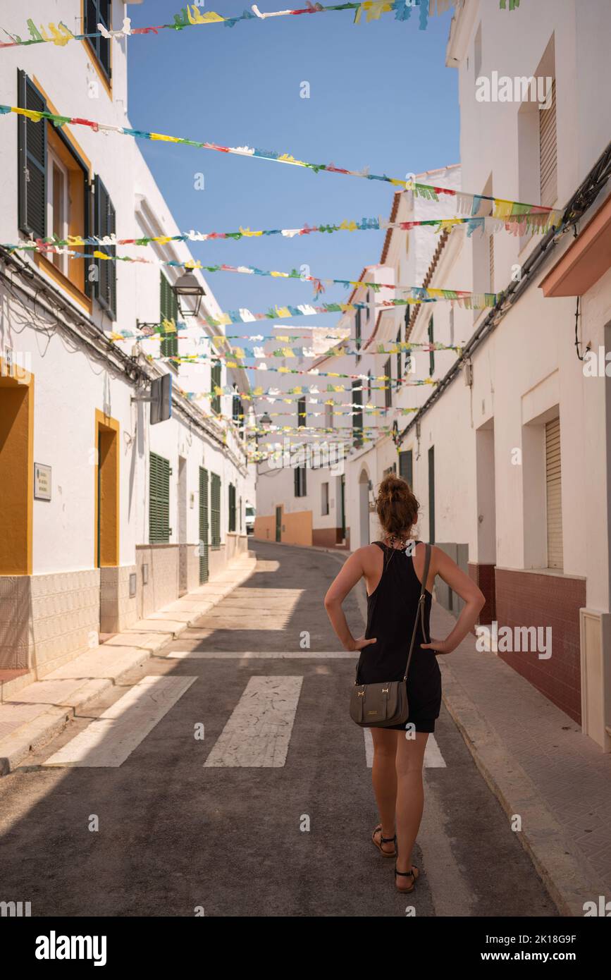 Dame, die im Sommer durch die Seitenstraßen der menorquinischen Stadt spazierengeht Stockfoto