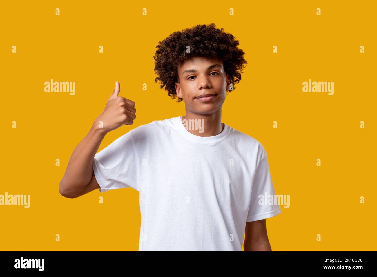 Wie Geste. Sozialer Druck. Verwirrt schwarz teen junge zeigt Daumen nach oben. Blick auf die Kamera isoliert auf orangefarbenem Kopierbereich. Genehmigungszeichen. Motivation de Stockfoto