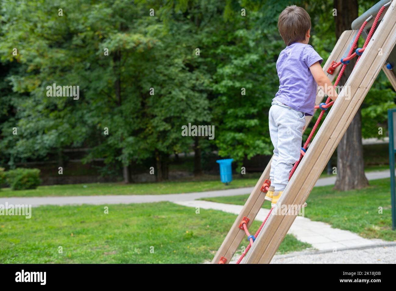 Ein Junge (nicht erkennbar) klettert auf einem Kinderspielplatz eine Seilleiter Stockfoto