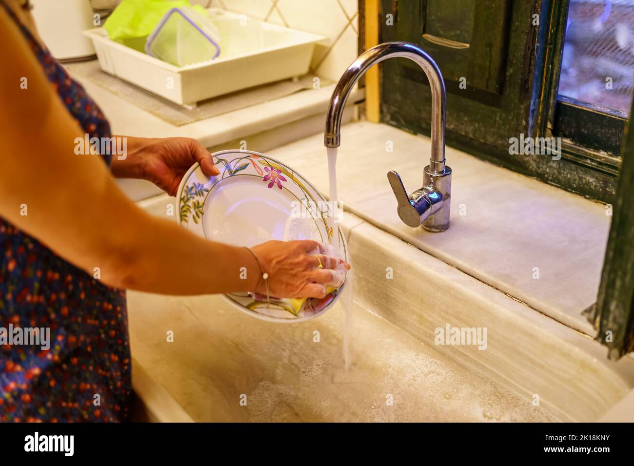 Frau, die Geschirr in einem antiken Retro-Küchenwaschbecken abwaschen. Stockfoto