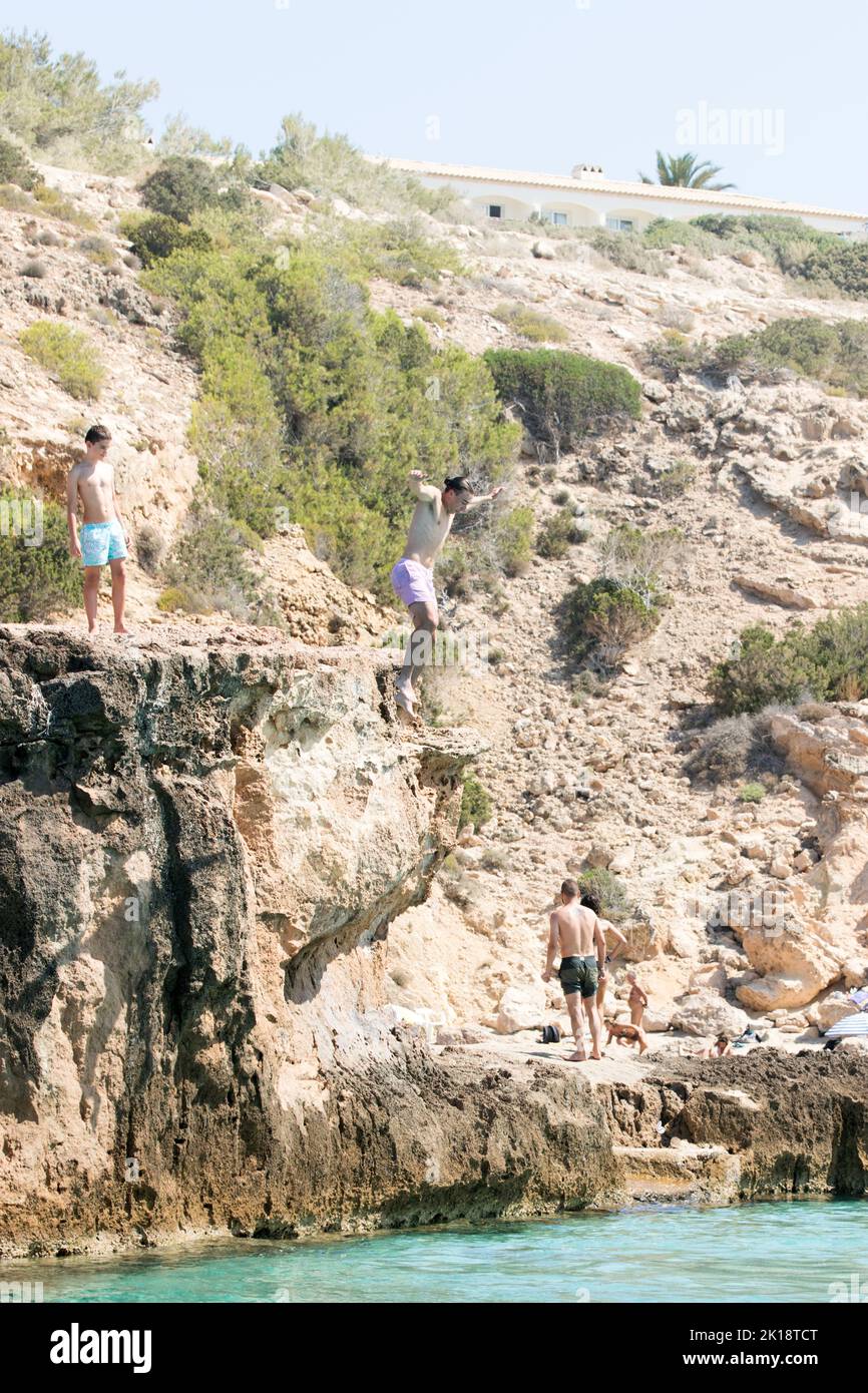Urlauber auf der Insel Ibiza genießen es, von einem Felsen ins Meer zu springen. Die Insel hat viele tiefe Buchten und felsige Aufschlüsse. Stockfoto