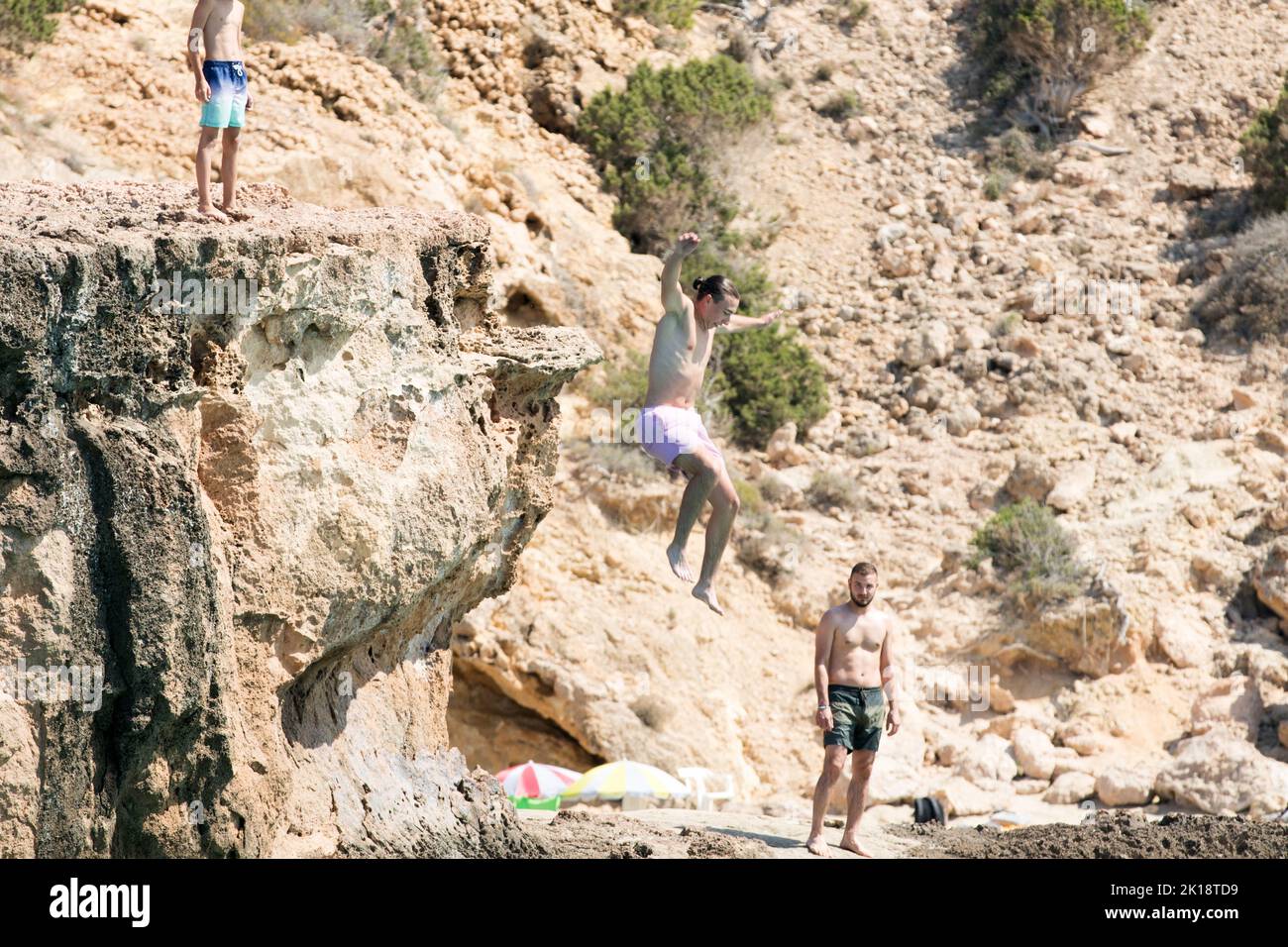 Urlauber auf der Insel Ibiza genießen es, von einem Felsen ins Meer zu springen. Die Insel hat viele tiefe Buchten und felsige Aufschlüsse. Stockfoto