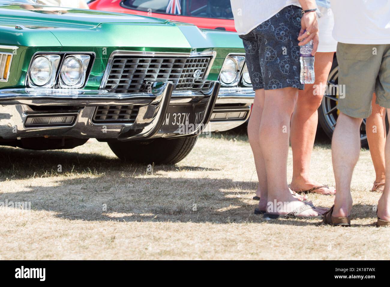 Blick auf die Beine von Autofans, die an einem Sommertag auf der Classic Car Show in Saffron Walden, Essex, Großbritannien, stehen und sprechen Stockfoto