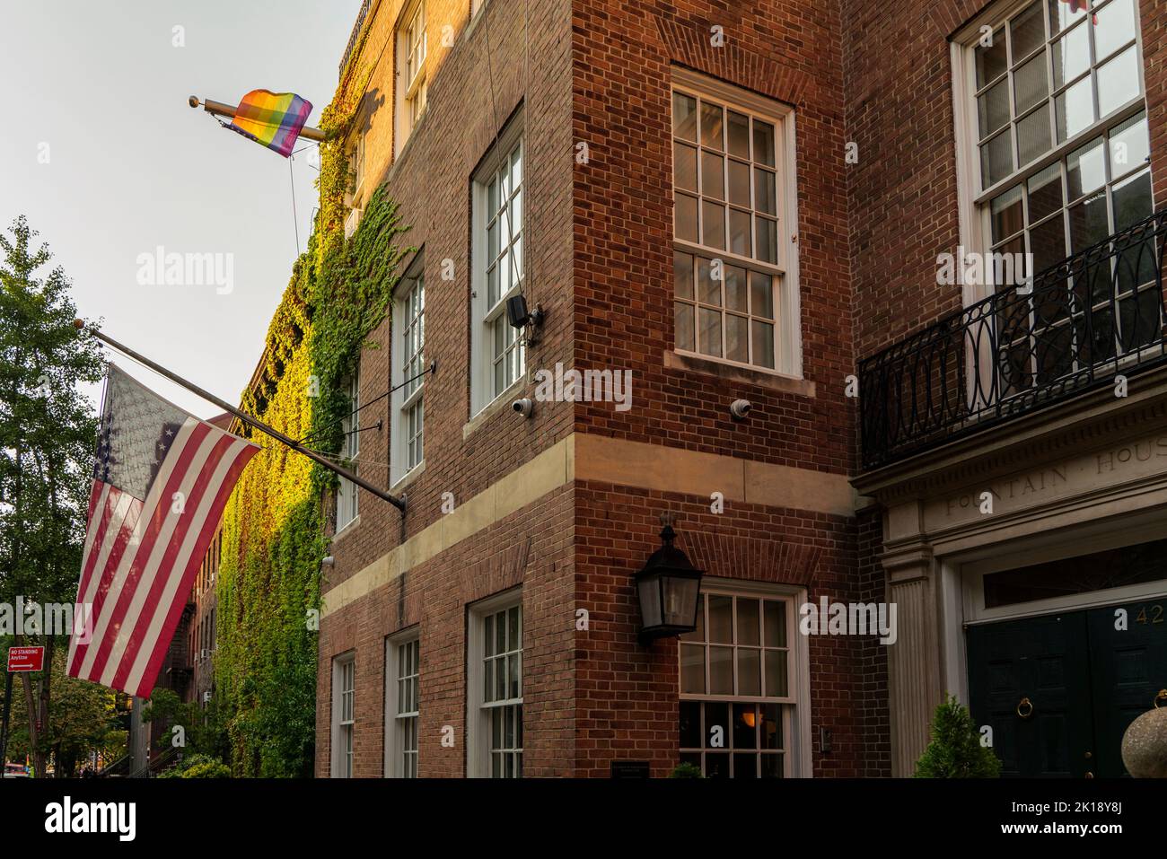 Amerikanische Flagge und LGBT-Flagge an der Fassade des alten Gebäudes und Blick auf die Straße am Abend. Stockfoto