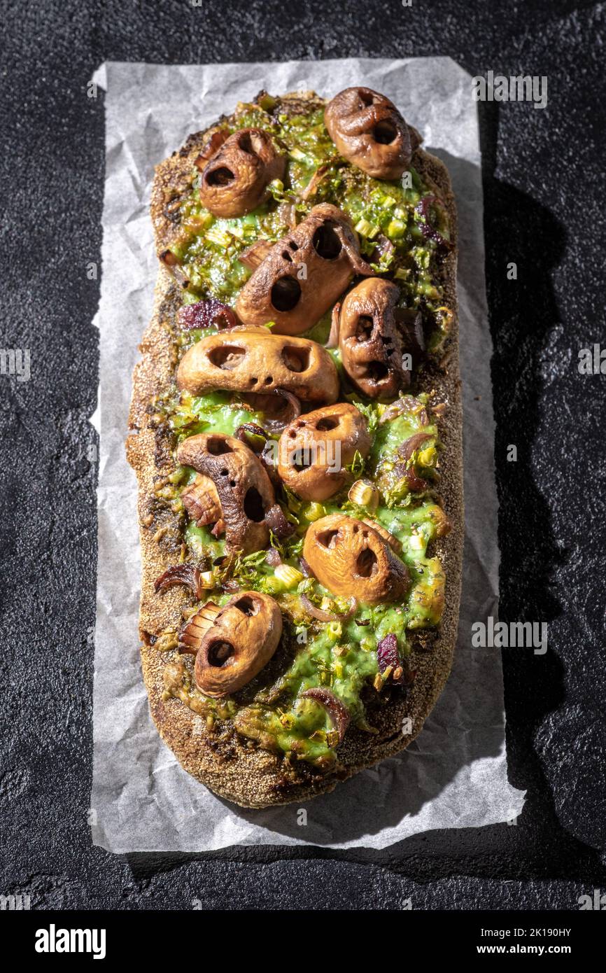 Halloween gruseliges Pizzabrot mit Totenkopf-förmigen Pilzen. Stockfoto