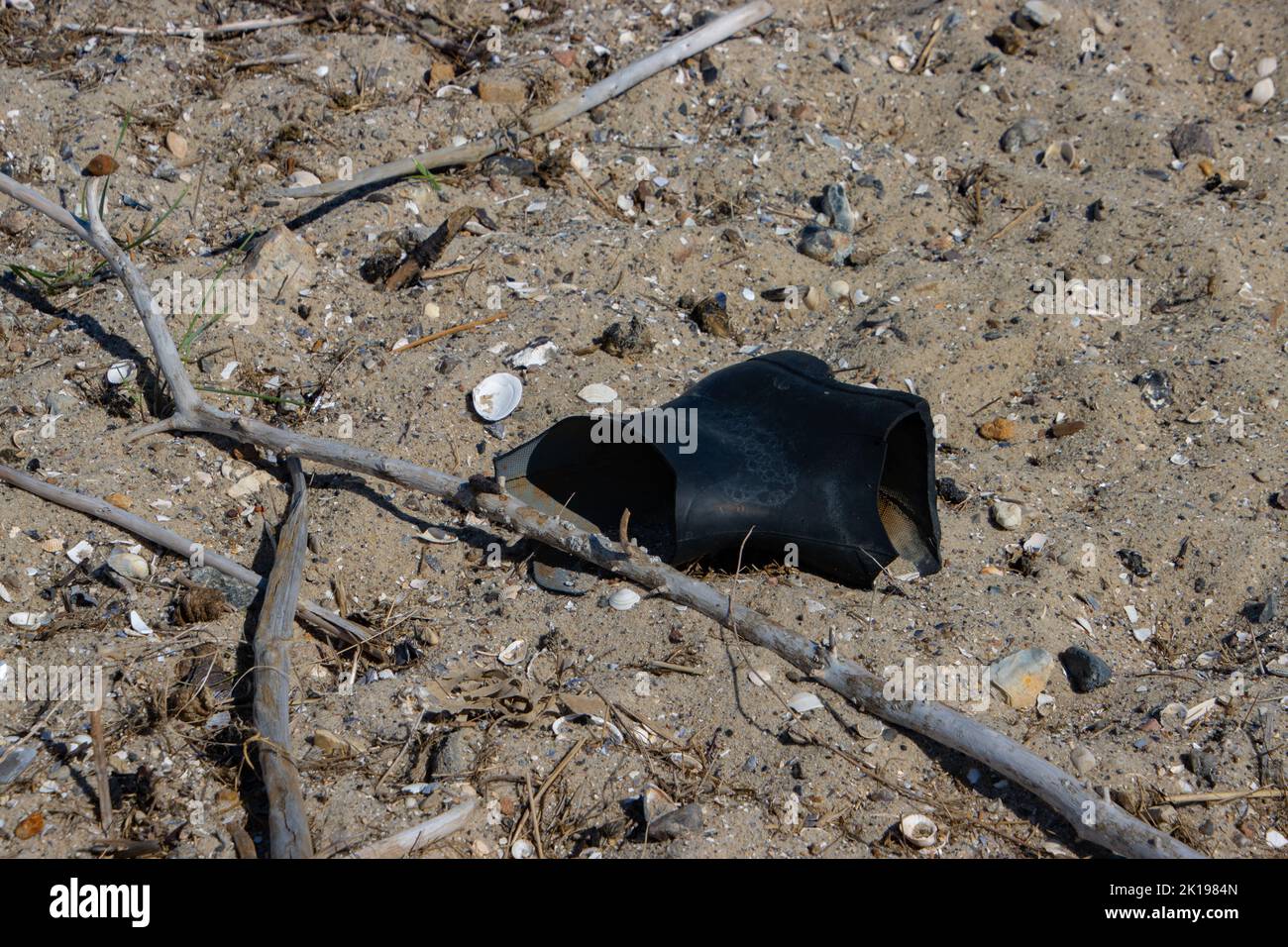 Alte schwarze zerschnittener Gummistiefel am Strand, Konzept der Umweltverschmutzung Stockfoto
