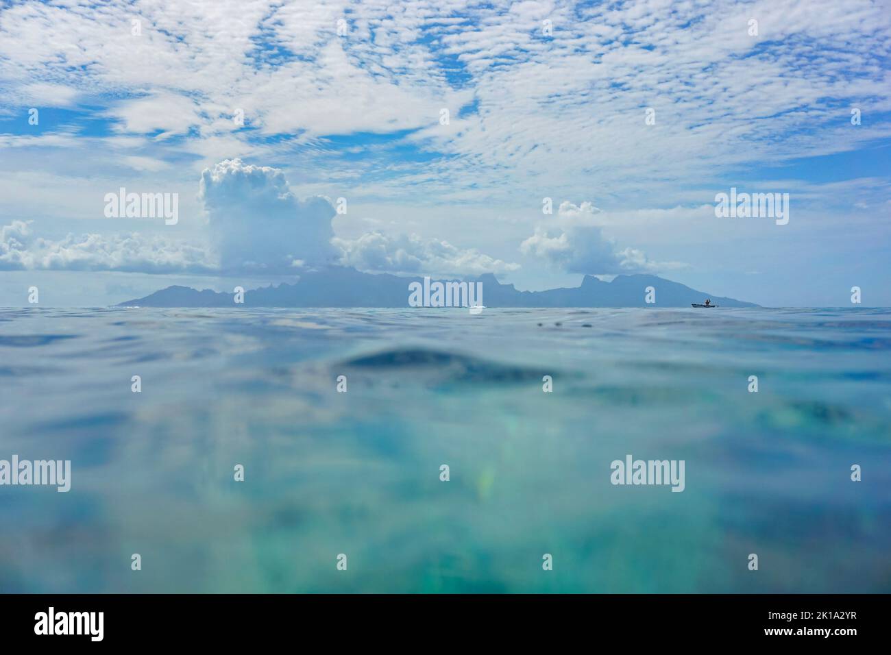 Moorea Insel am Horizont von der Wasseroberfläche aus gesehen mit blauem Himmel und Wolken, tropischer Meereslandschaft, Südpazifik, Französisch-Polynesien Stockfoto