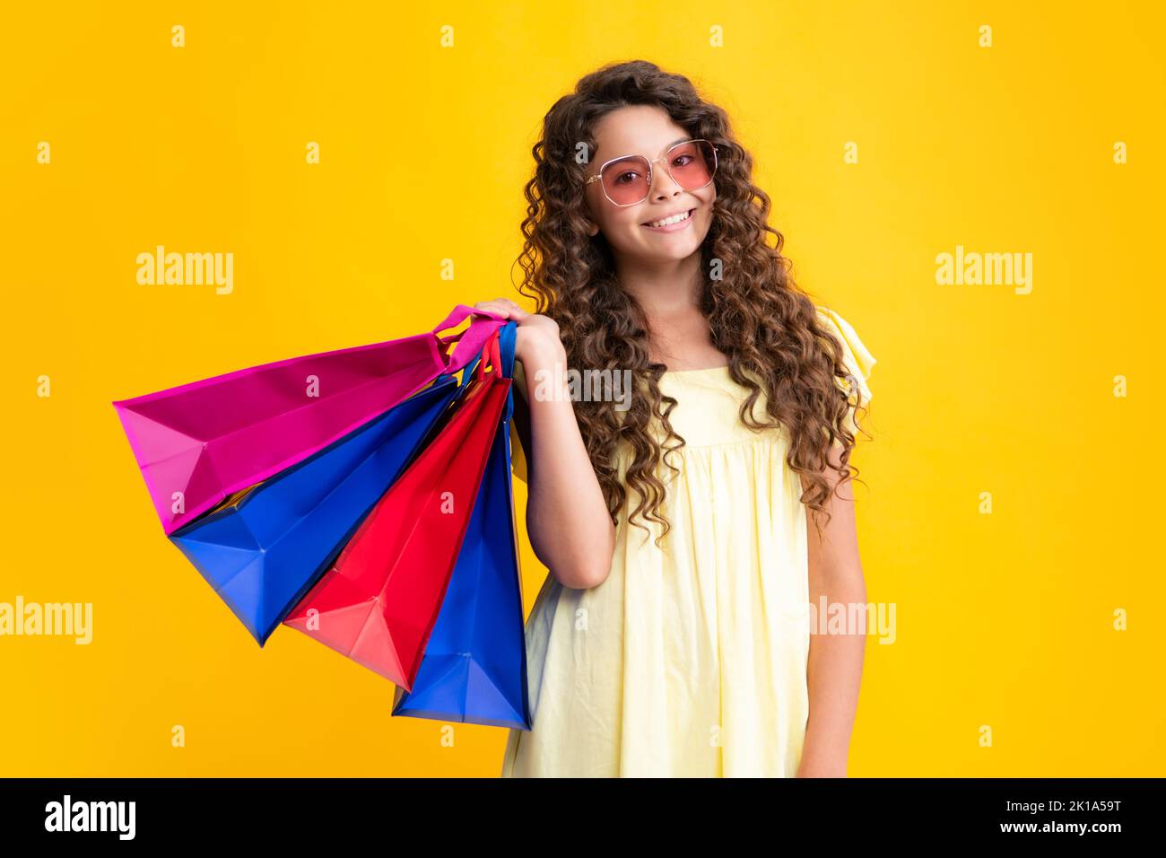Sommer-Shopping-Angebot. Schöne Mode Teenager Mädchen mit Einkaufstaschen auf gelbem Hintergrund. Shopaholic Shopping und Mode. Kind mit Stockfoto